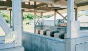 山口県長門市の大浜キャンプ場にある、木とコンクリートで造られたバーベキュー施設。自然に囲まれ、奥には建物が見える。