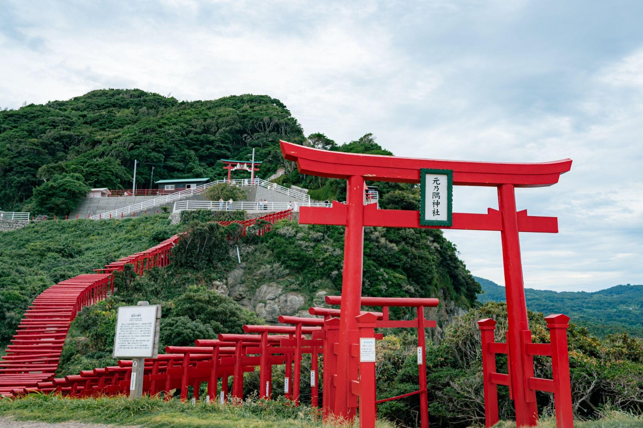 元乃隅神社の、海を見下ろす丘の斜面に沿って何百もの朱色の鳥居が連なっている風景。