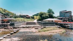 山口県の長門湯本温泉。音信川の飛び石と、丘に続く温泉街の美しい景色が広がります。